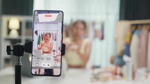 Asia lady vlogger look phone camera apply lipstick on skin live sale online viral video selfie.