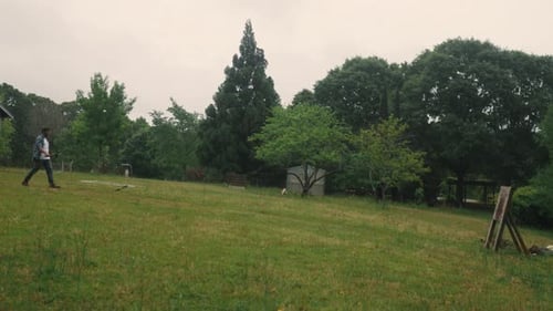 Man Walking Across Green Field on Overcast Day