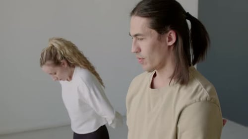 Young Adults Practicing Yoga Exercises in Bright Studio