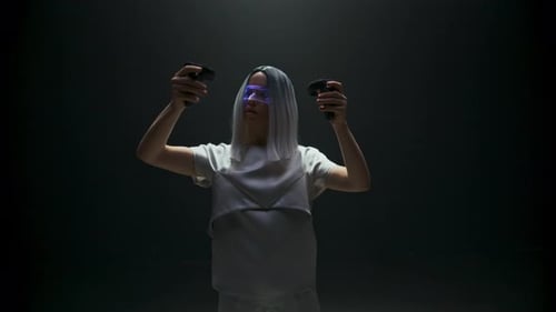 Focused young woman immersed in futuristic vr game in bright studio light