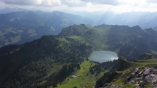 Drone flying backwards while a young, fit man is running down the rocky trail on the edge of the rid