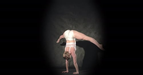Un acróbata flexible en el centro de atención del escenario se pone de pie de manos con una pose de escorpión