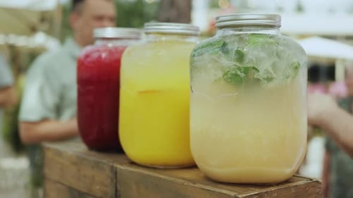 A Row of Jars with Various Fruit Juices on a Wooden Table