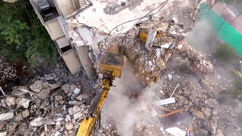Excavator arm demolishing an old building, Aerial view