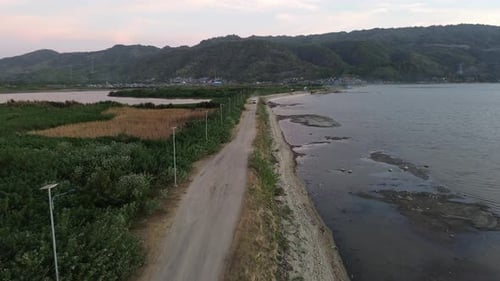 Aerial view of vehicles driving on a road crossing the Limboto Lake