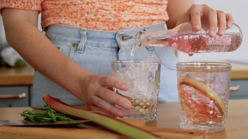 Drinks And People Concept - Young Woman Making Rhubarb Cocktail And Decorating It With Sprig Of R...