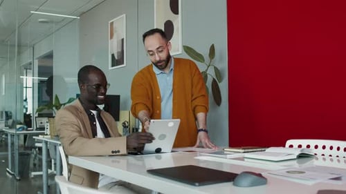 Männlicher Designer demonstriert Kollegen neue Arbeiten auf dem Tablet