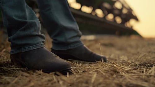Agronomist Boots Stand Field at Harvester Straw Closeup. Unknown Combine Operator Checking