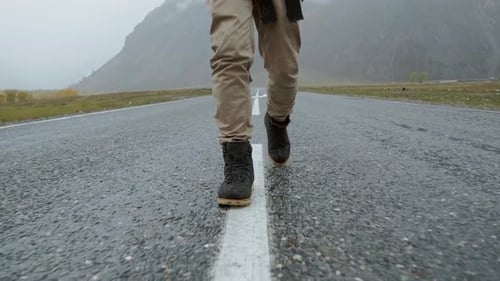 Traveler Man Hitchhiking Along the Road and Walking Uses the Phone