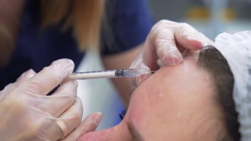 Beautician Doctor Makes Botox Injection in the Forehead of Young Beautiful Woman Extreme Close Up