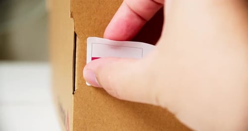 Applying Made In Poland Sticker on Cardboard Box