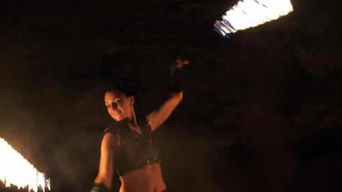 Woman Performing Fire Dance in Dark Environment