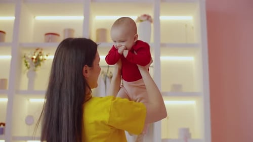 Mother Holding Smiling Baby in Bright Room