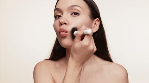 Beautiful Woman Applying Makeup with Brush Studio Shot