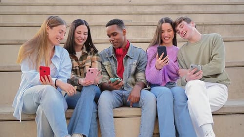 Smiling Young Adults Using Smartphones Outdoors on Steps