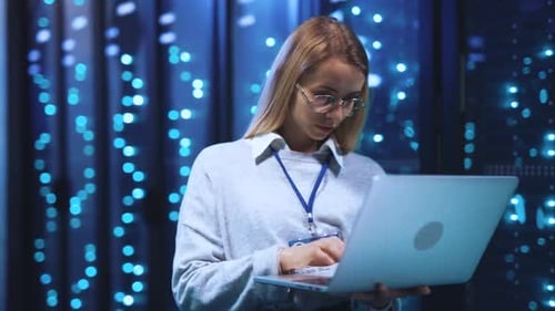 A Focused Woman Works on Her Laptop in a Hightech Server Room