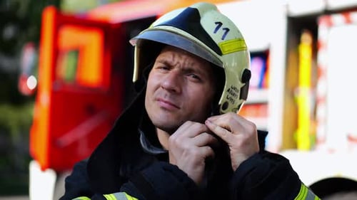 Firefighter Adjusting Helmet near Fire Truck