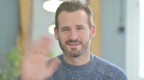 Mann mittleren Alters winkt mit der Hand, um Hallo zu sagen