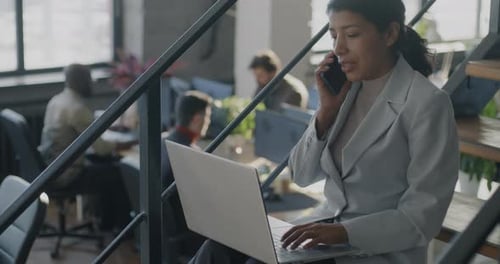 Woman Works on Laptop While on Phone