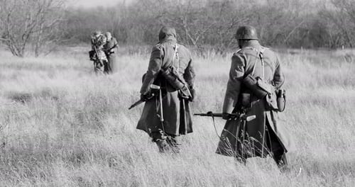 Reenactors Dressed As German Infantry Soldiers In World War II Marching Walking Along Meadow In Cold