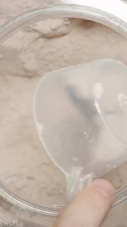 Vertical video. Athlete pouring Protein Powder back into the container, changing their mind about