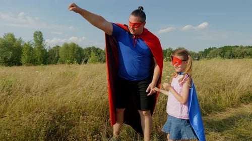 Father and Daughter Play Superhero in Field