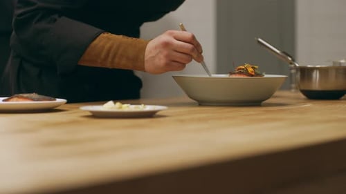 Chef carefully plates dish in restaurant kitchen