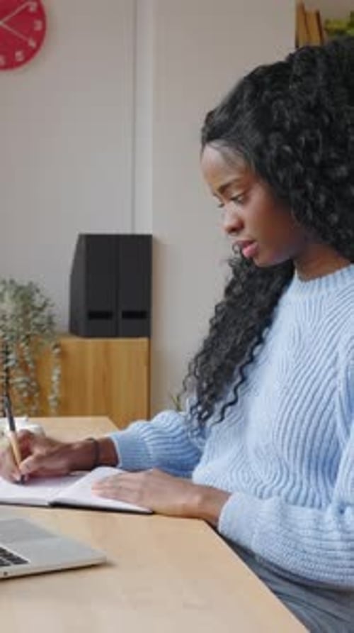 Young Latin American Female Student Taking Notes While Studying Online at Home