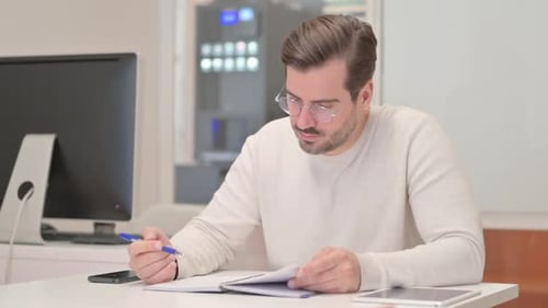 Reading Young Man Checking Documents in Office