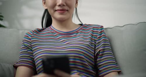 Woman Using Phone Sitting on Sofa at Home