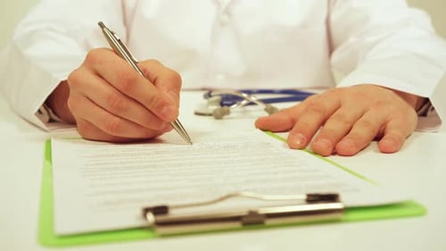 Doctor Writes on Chart in Office Setting