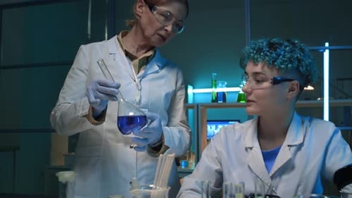 Two Female Scientists Discussing Liquid Samples in Chemistry Lab