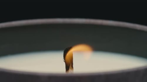 Close up of lit candle wick being blown out and smoking in slow motion