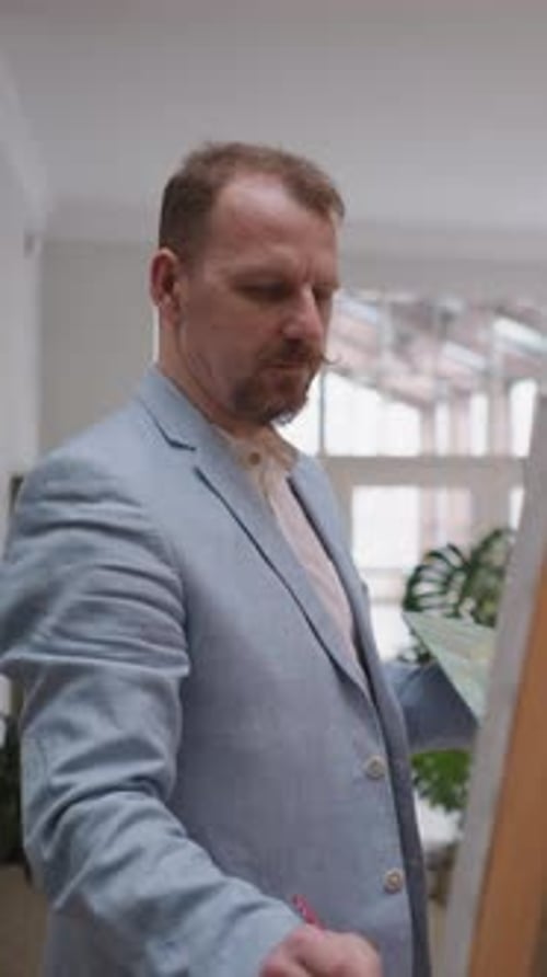 Bearded Artist Works at Easel in Studio