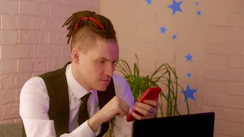 Man Using Phone and Laptop Indoors