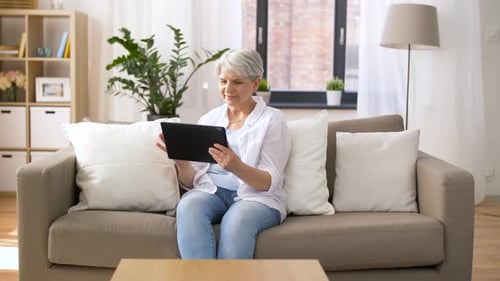 Senior woman using tablet on couch at home