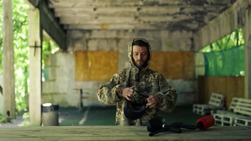 Dans la nature, dans le hangar pour recevoir des instructions, un entraîneur de pintball revêt un uniforme avant la fin du match