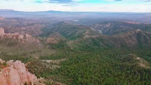 Mountainous panorama on cloudy daytime. Drone footage over the rocky landscape overgrown