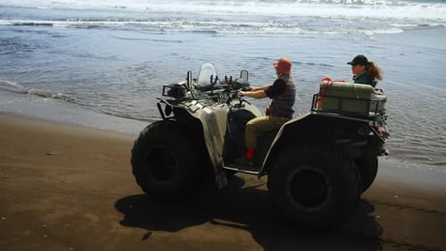 Tourist Enjoying Freedom And Beauty Of Nature On Ocean Coastline Riding Quad On Sandy Beach