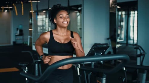 Young African American Woman Exercises on Treadmill in Modern Gym Setting