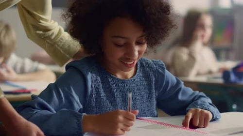 Elementary School Girl Studies in Classroom with Teacher