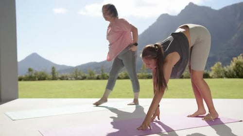 Exercising outdoors, women stretching on yoga mats with scenic mountain view