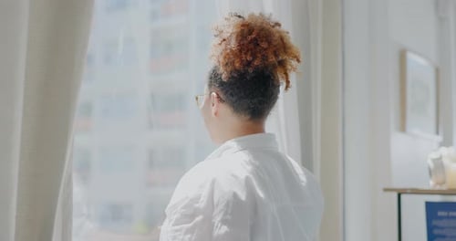 Woman Opens Curtains Looking at City