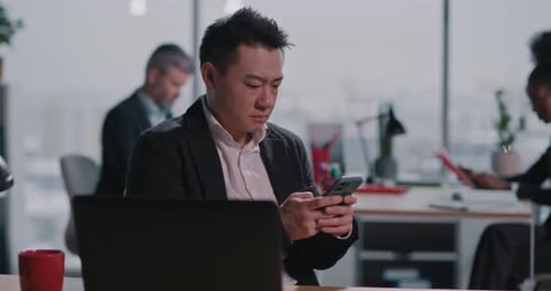 Man Uses Phone at Desk in Modern Office