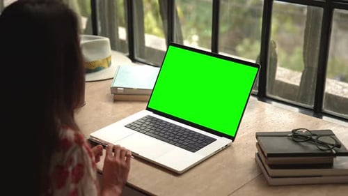 Mujer trabajando en una computadora portátil o mirando una videollamada en línea en pantalla verde