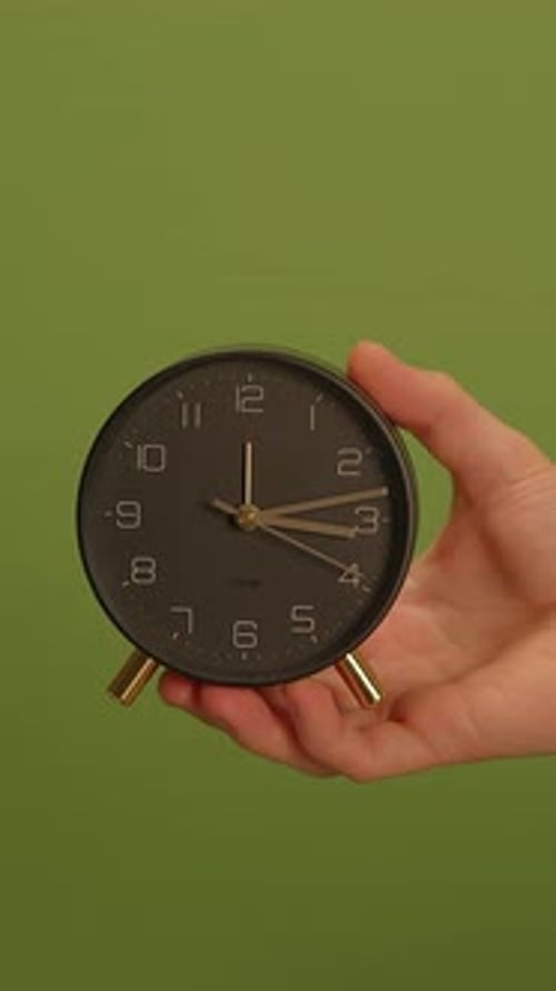 A Black Clock Against a Vibrant Green Background Showcasing Its Unique Design and Elegance