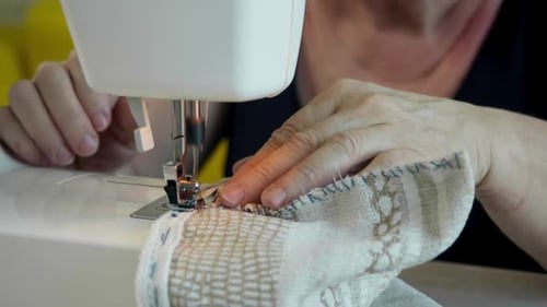 Adult Using Sewing Machine to Sew Fabric