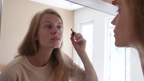 Beautiful woman making up by the mirror in hotel room
