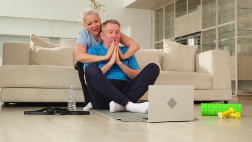 Senior Couple Exercising Together at Home with Laptop