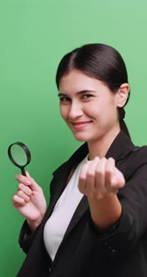 Vertical clip. Female human resources manager looking at something with a magnifying glass.